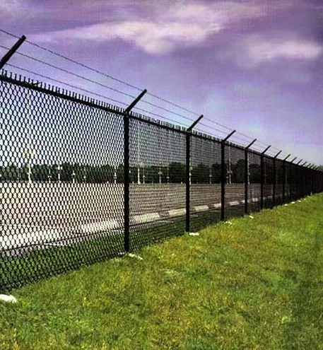 Black vinyl-coated chain link security fence with barbed wire installed around a commercial lot by Durable Fence
