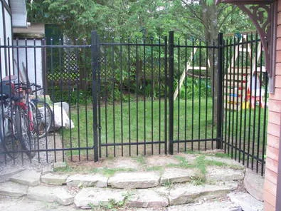 Secure black iron gate and panels forming a pet-safe side yard entry built by Durable Fence