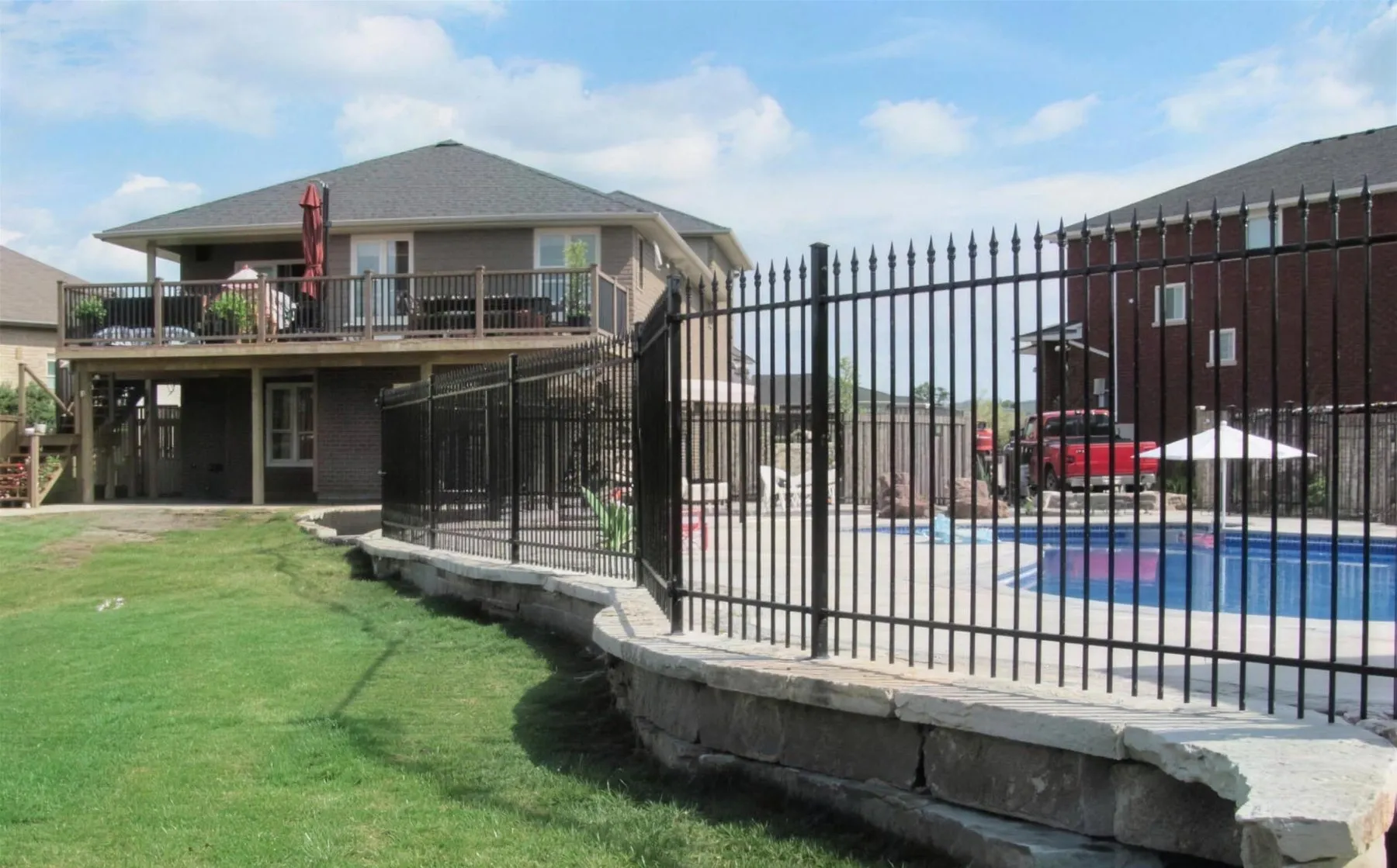 Iron pool fence following a curved stone retaining wall